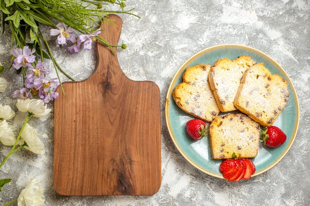 Vue de dessus de délicieuses tranches de gâteau avec des fraises à la lumière