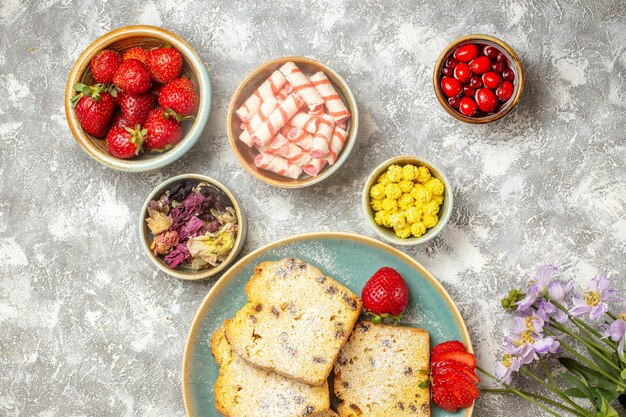 Vue de dessus de délicieuses tranches de gâteau avec des fruits et des bonbons à la lumière