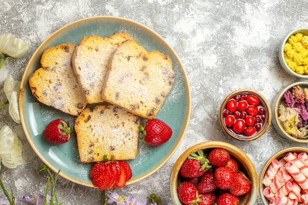 Vue de dessus de délicieuses tranches de gâteau avec des fruits et des bonbons à la lumière