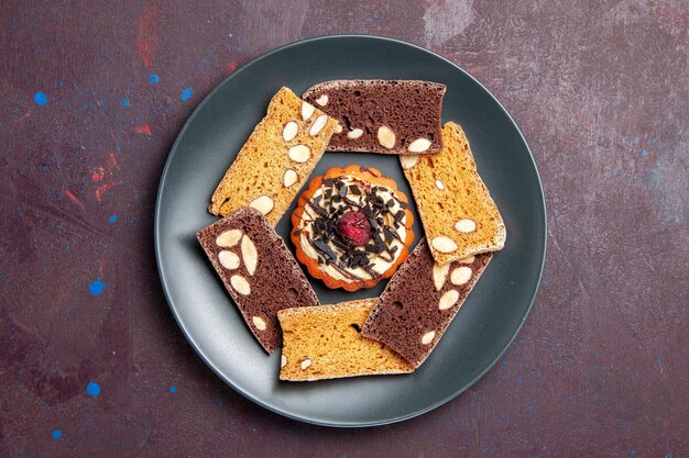 Vue de dessus de délicieuses tranches de gâteau avec noix et petit biscuit sur fond sombre biscuit biscuit gâteau dessert sucré