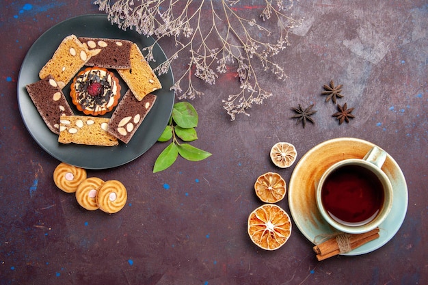 Vue de dessus de délicieuses tranches de gâteau avec une tasse de thé sur fond noir