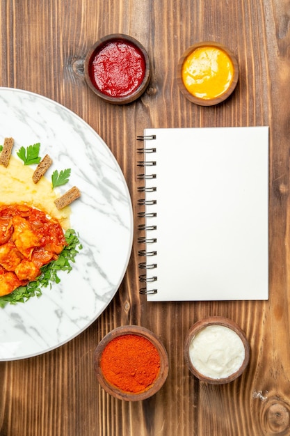 Vue de dessus de délicieuses tranches de poulet avec assaisonnements et purée de pommes de terre sur une table brune. plat poivre viande repas dîner