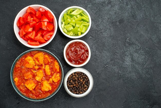 Vue de dessus de délicieuses tranches de poulet avec sauce tomate et légumes frais sur fond sombre plat de sauce au poulet viande de tomate