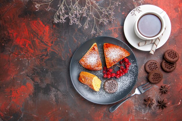 Vue de dessus de délicieuses tranches de tarte aux fruits rouges sur le gâteau de table sombre thé à tarte sucrée