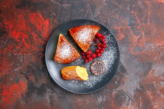 Vue de dessus de délicieuses tranches de tarte aux fruits rouges sur le gâteau de tarte sucrée de table sombre