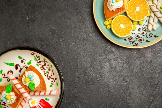 Vue de dessus de délicieuses tranches de tarte aux mandarines tranchées sur fond gris foncé gâteau aux bonbons aux fruits thé à la pâte à tarte