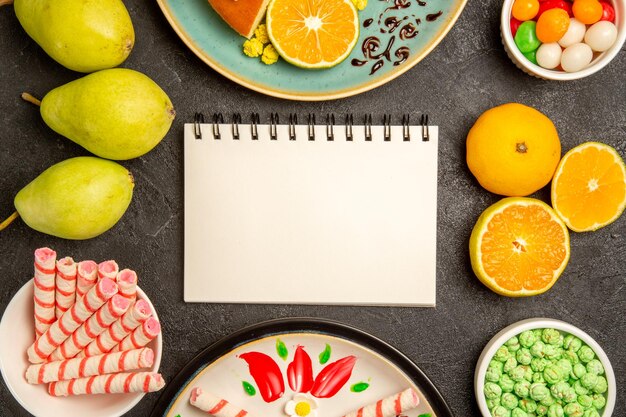 Vue de dessus de délicieuses tranches de tarte avec des mandarines fraîches et des poires sur fond gris tarte aux fruits pâte à sucre gâteau au thé