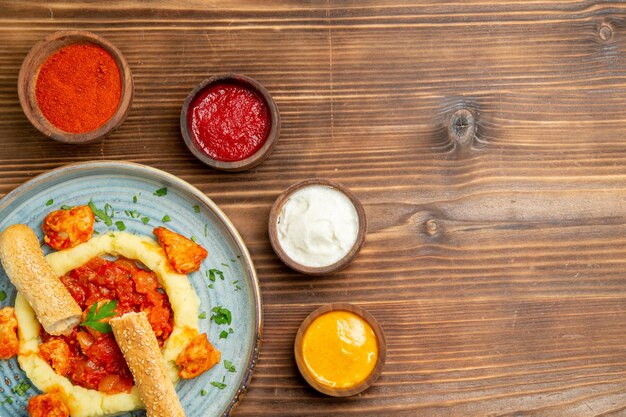 Vue de dessus de délicieuses tranches de viande avec purée de pommes de terre et assaisonnements sur un plat de bureau brun repas de viande pommes de terre pain nourriture