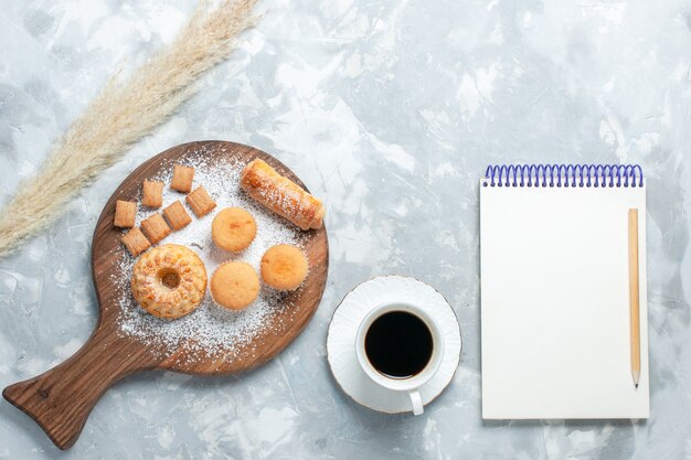 Vue de dessus délicieux bagel avec tasse de thé et gâteaux sur fond blanc clair.