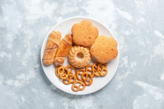 Vue de dessus de délicieux bagels avec des biscuits et des gâteaux à l'intérieur de la plaque sur un bureau blanc clair.