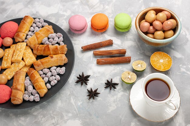 Vue de dessus de délicieux bagels avec des craquelins macarons à la cannelle et des cookies sur le gâteau de bureau blanc biscuit tarte au sucre sucré biscuit croustillant