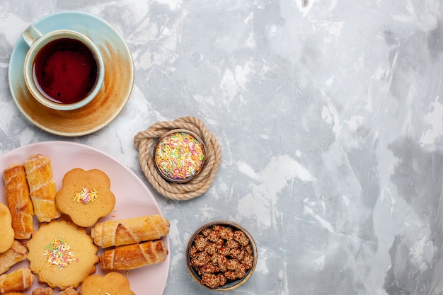 Vue de dessus de délicieux bagels avec des gâteaux et du thé sur un bureau blanc