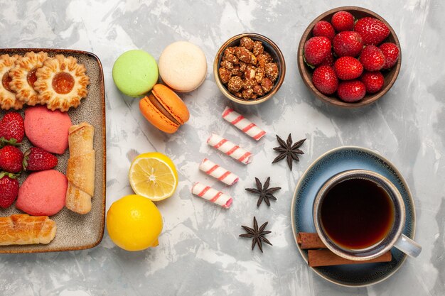 Vue de dessus de délicieux bagels avec des gâteaux thé fraises fraîches et biscuits sur le bureau blanc