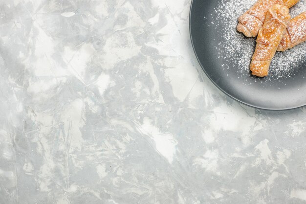 Vue de dessus de délicieux bagels sucrés en poudre sur un bureau blanc