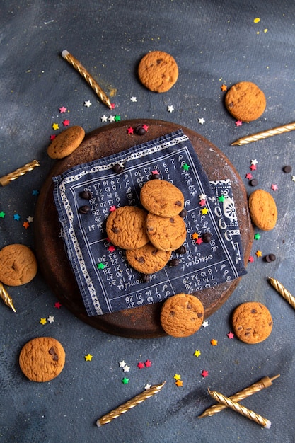 Vue de dessus de délicieux biscuits au chocolat avec des bougies sur le bureau gris foncé biscuit biscuit sucre sucré