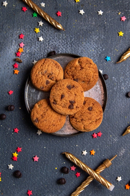 Vue de dessus de délicieux biscuits au chocolat à l'intérieur de la plaque avec de petits signes et des bougies sur le fond sombre biscuit biscuit sucre thé sucré