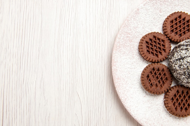 Vue de dessus délicieux biscuits au chocolat avec petit gâteau au cacao sur blanc