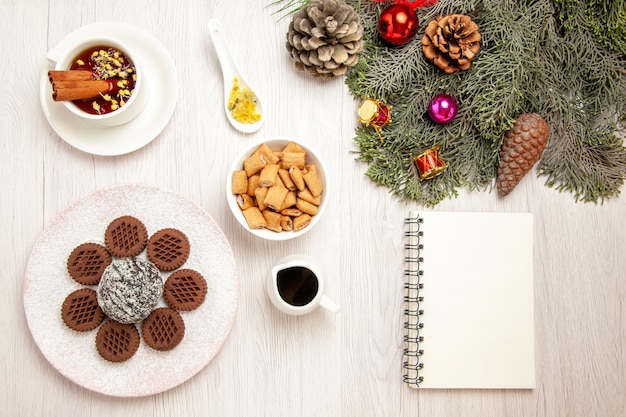 Vue de dessus délicieux biscuits au chocolat avec petit gâteau au cacao et thé sur le bureau blanc