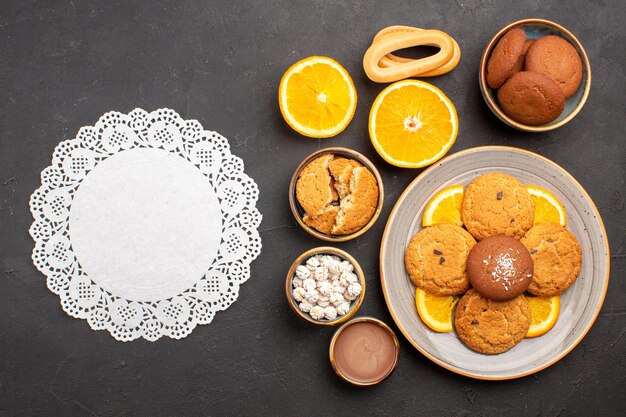 Vue de dessus de délicieux biscuits au sable avec des tranches d'oranges sur le fond sombre biscuit aux agrumes aux fruits biscuit au gâteau sucré