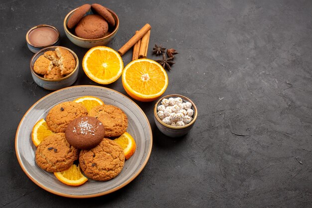 Vue de dessus de délicieux biscuits au sable avec des tranches d'oranges fraîches sur fond sombre biscuit aux fruits biscuit sucré au sucre d'agrumes