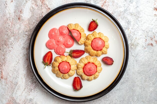 Vue de dessus de délicieux biscuits au sucre avec de la gelée de fraise sur une surface blanche