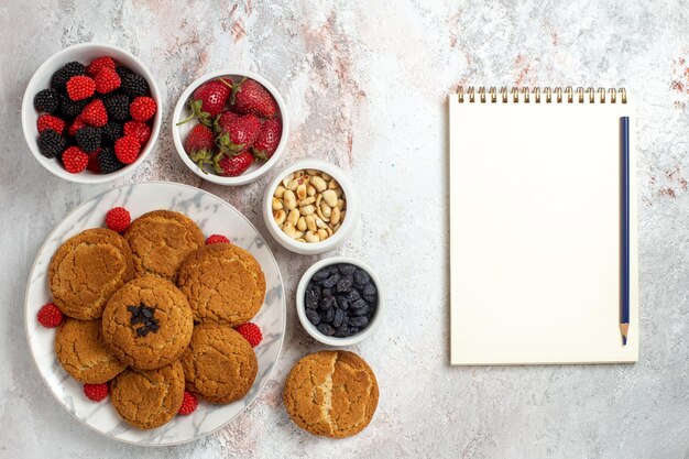 Vue de dessus de délicieux biscuits au sucre avec des noix sur une surface blanche