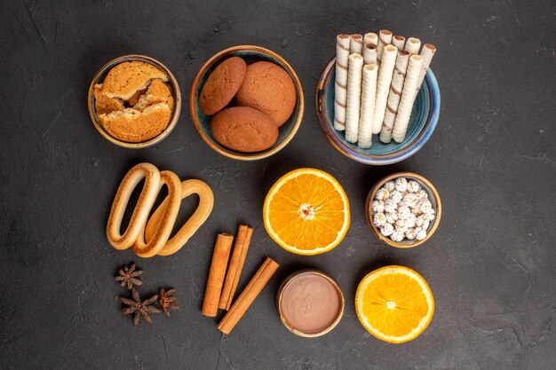 Vue de dessus de délicieux biscuits au sucre avec des tranches d'oranges sur fond sombre biscuits au thé au sucre biscuits aux fruits sucrés