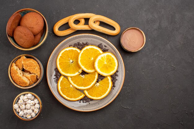Vue de dessus de délicieux biscuits au sucre avec des tranches d'oranges fraîches sur fond sombre biscuits biscuit gâteau au sucre dessert sucré