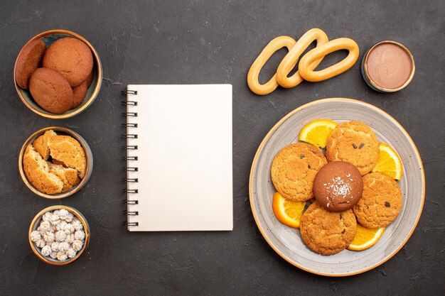 Vue de dessus de délicieux biscuits au sucre avec des tranches d'oranges fraîches sur fond sombre biscuits biscuit gâteau au sucre dessert sucré