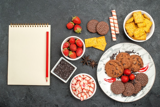 Vue de dessus délicieux biscuits choco avec différentes collations sur fond sombre biscuits sucrés