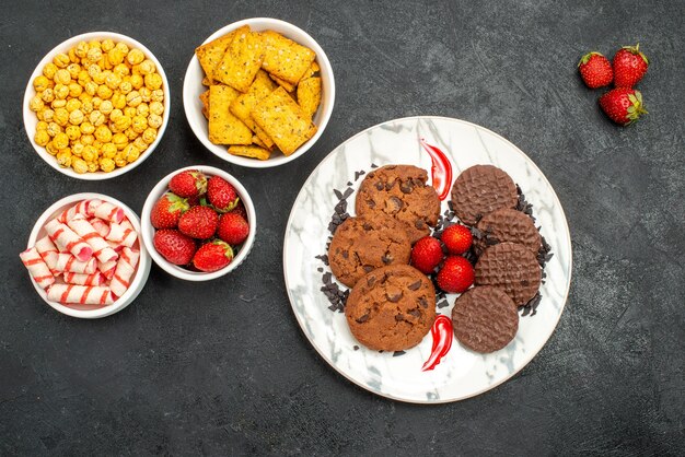 Vue de dessus délicieux biscuits choco avec différentes collations sur fond sombre thé biscuits sucrés