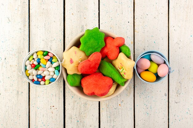 Vue de dessus de délicieux biscuits colorés différents formés plaque intérieure multicolore avec des bonbons sur la surface grise