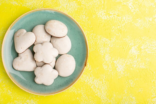 Vue de dessus de délicieux biscuits délicieux à l'intérieur de la plaque sur la surface jaune