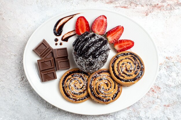 Vue de dessus de délicieux biscuits avec un gâteau au chocolat et des fraises sur un espace blanc