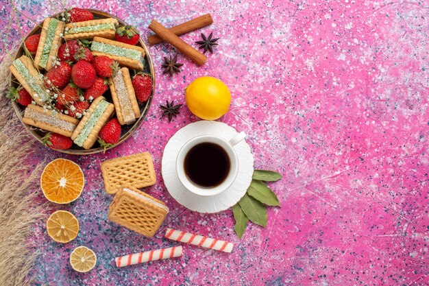 Vue de dessus de délicieux biscuits gaufres avec des fraises rouges fraîches sur la surface rose