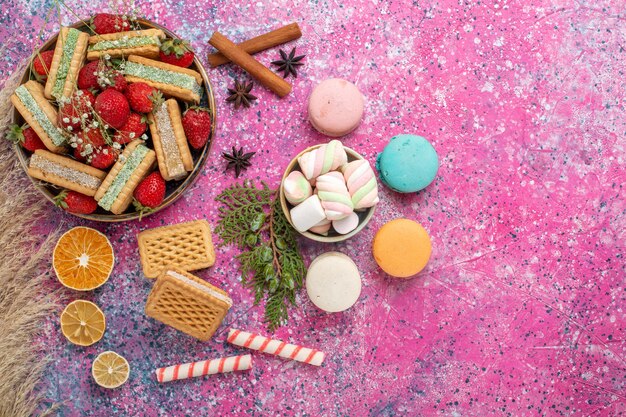 Vue de dessus de délicieux biscuits gaufres avec des fraises rouges fraîches sur la surface rose