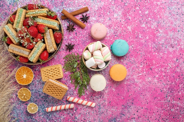 Vue de dessus de délicieux biscuits gaufres avec des fraises rouges fraîches sur la surface rose