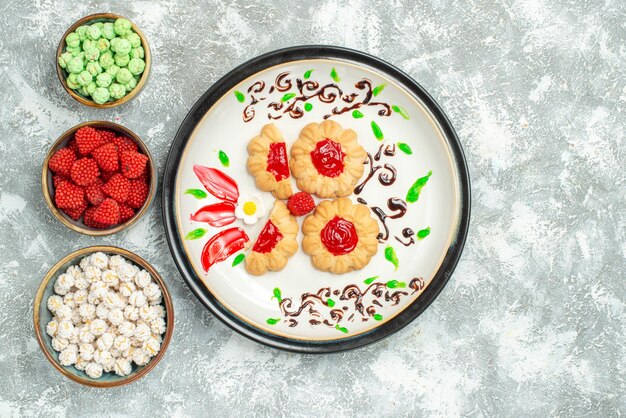 Vue de dessus de délicieux biscuits avec de la gelée rouge et des bonbons sur fond blanc biscuit gâteau biscuit thé sucré