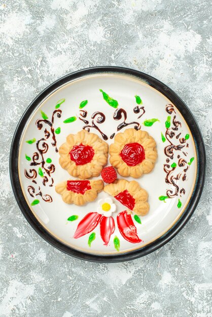 Vue de dessus de délicieux biscuits avec de la gelée rouge à l'intérieur de la plaque sur fond blanc gâteau cookie thé sucré