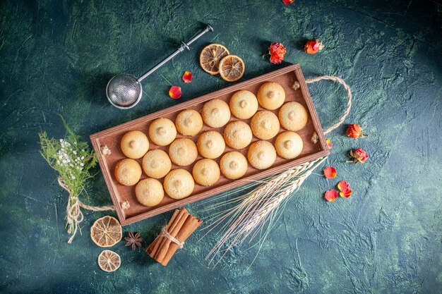 Vue de dessus de délicieux biscuits à l'intérieur d'une boîte en bois sur fond bleu foncé biscuit au sucre tarte aux biscuits couleur gâteau au thé aux noix sucrées