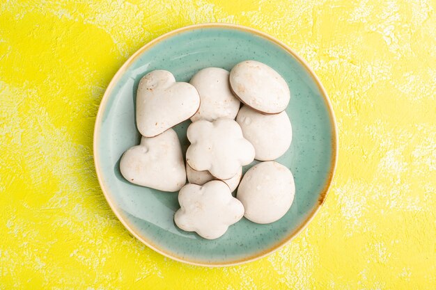 Vue de dessus de délicieux biscuits à l'intérieur de la plaque verte sur la surface jaune