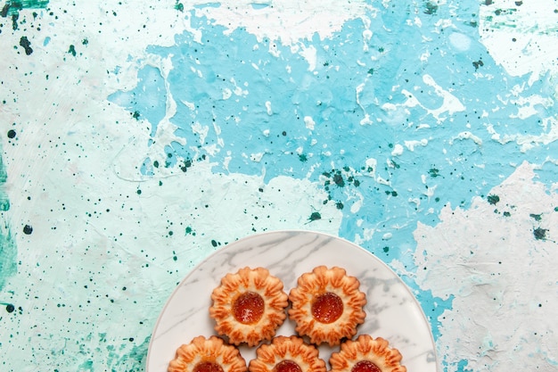 Vue de dessus de délicieux biscuits rond formé avec de la confiture à l'intérieur de la plaque sur le fond bleu clair biscuit sucre gâteau biscuit sucré