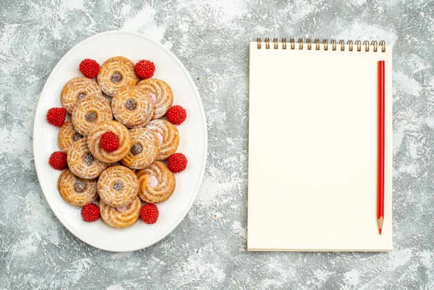 Vue de dessus de délicieux biscuits ronds avec des confitures de framboises sur un espace blanc