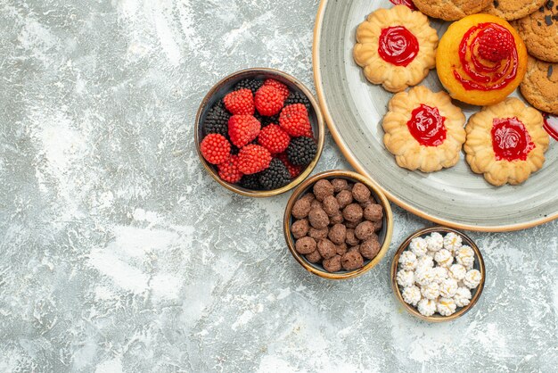 Vue de dessus délicieux biscuits de sable avec des biscuits et des bonbons sur blanc