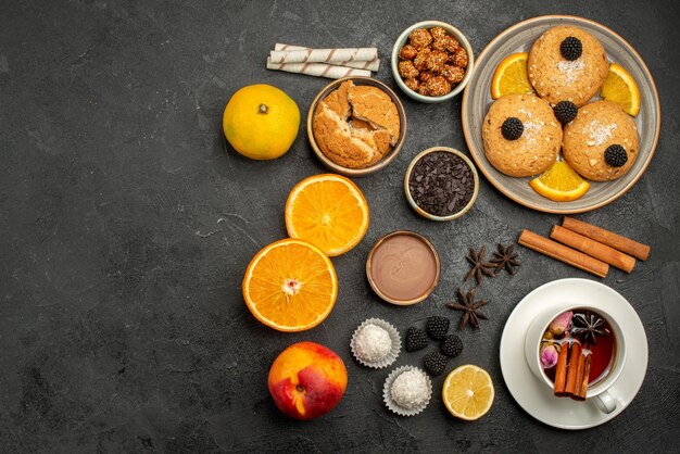 Vue de dessus de délicieux biscuits avec une tasse de thé et d'orange sur un gâteau aux biscuits au thé à la surface sombre