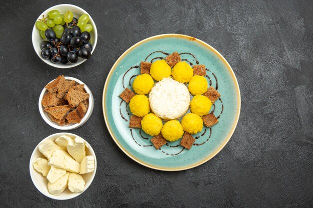 Vue de dessus de délicieux bonbons jaunes avec du gâteau aux raisins et au fromage sur fond sombre sucre aux fruits bonbons au thé gâteau sucré