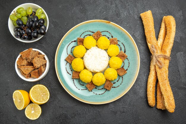 Vue de dessus de délicieux bonbons jaunes avec des raisins à gâteau et du pain sur fond sombre sucre bonbons aux fruits gâteau au thé sucré