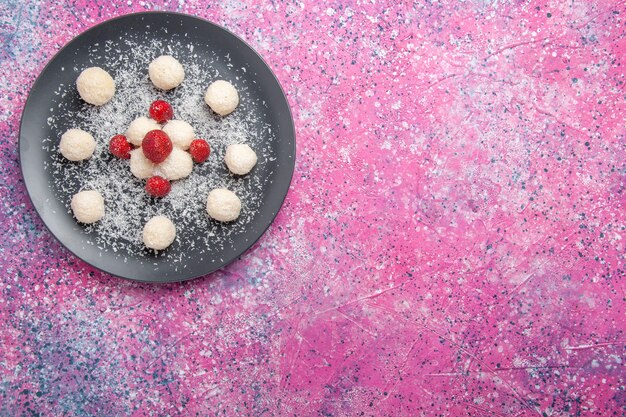 Vue de dessus de délicieux bonbons à la noix de coco boules sucrées sur le plancher rose bonbons au sucre gâteau sucré