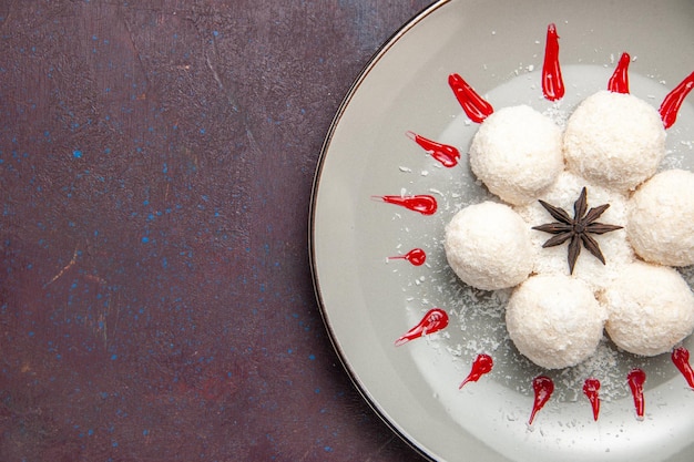 Vue de dessus de délicieux bonbons à la noix de coco avec glaçages rouges sur tableau noir