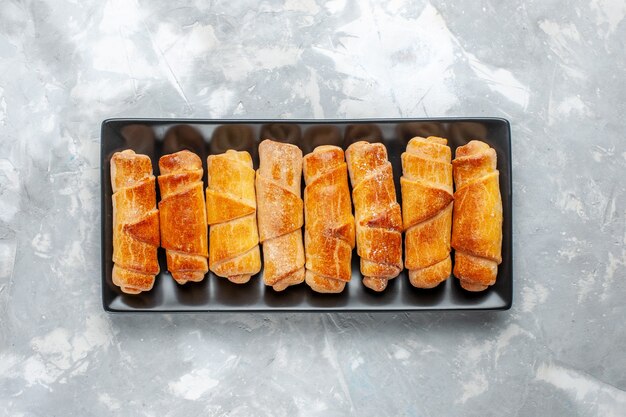 Vue de dessus de délicieux bracelets cuits à l'intérieur de la moisissure noire sur blanc, pâtisserie cuire au four gâteau aux biscuits sucré